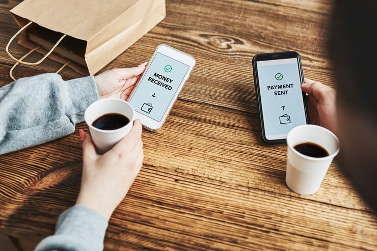 How Cash Transfer Online Works Two People Sitting at a Wooden Table, Holding Coffee Cups and Smartphones Displaying "Money Received" and "Payment Sent"