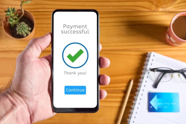 Secure and Reliable Payment Processing A Person Holding a Smartphone Displaying a "Payment Successful" Confirmation Screen with a Green Checkmark