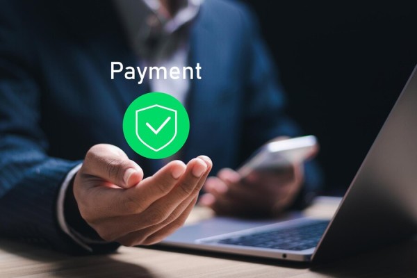 Secure and Reliable Vendor Payment Processing A Businessman Using a Laptop and Mobile Device with a Digital "Payment" Icon and a Green Checkmark Floating Above His Hand