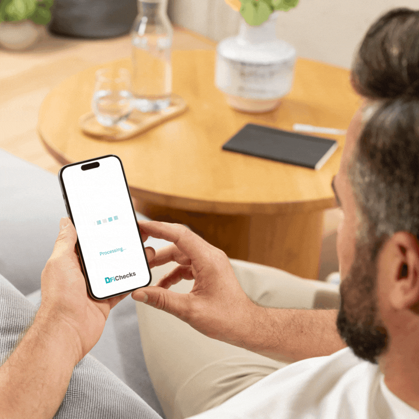 Man Using the FiChecks Mobile App on a Smartphone to Process a Digital Payment, Seated Comfortably in a Modern Living Room Setting